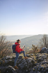 Frau auf einem Wanderausflug in den Bergen hält Karte und genießt schöne Aussicht - BSZF00946