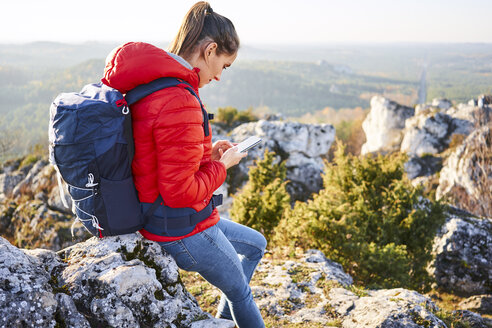 Frau beim Wandern in den Bergen, die ihr Mobiltelefon überprüft - BSZF00949