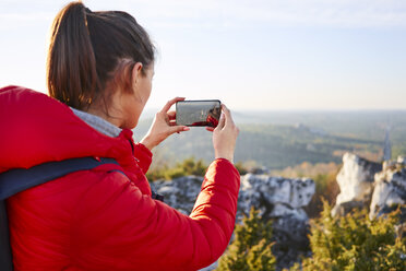 Frau auf einer Wanderung in den Bergen, die ein Smartphone-Foto macht - BSZF00950