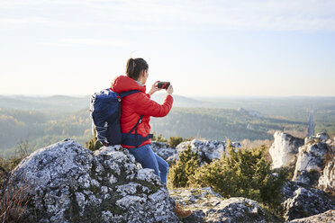 Frau auf einer Wanderung in den Bergen, die ein Smartphone-Foto macht - BSZF00951