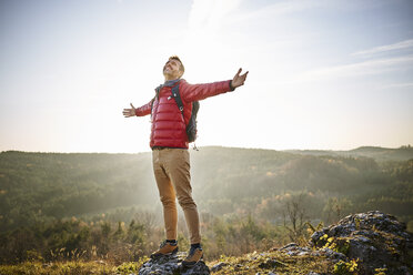 Mann auf einer Wanderung in den Bergen auf einem Felsen stehend und die Natur genießend - BSZF00958