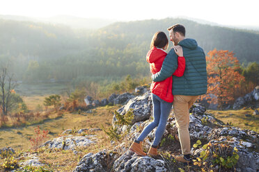 Rear view of couple on a hiking trip in the mountains standing on rock - BSZF00961