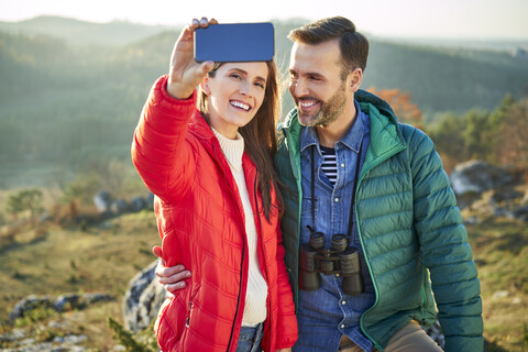 Glückliches Paar auf einem Wanderausflug in den Bergen, das ein Selfie macht, lizenzfreies Stockfoto