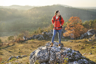 Frau beim Wandern in den Bergen auf einem Felsen stehend - BSZF00964