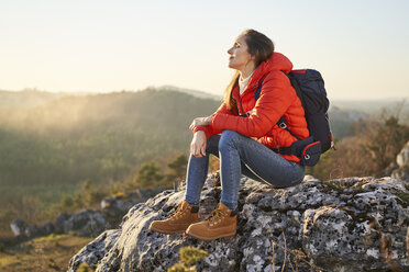 Woman on a hiking trip in the mountains resting on a rock - BSZF00965