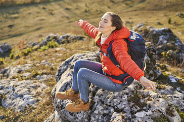 Frau bei einer Wanderung in den Bergen, die sich auf einem Felsen ausruht - BSZF00966