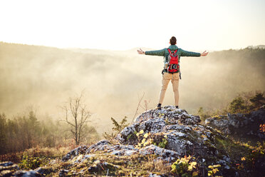 Man on a hiking trip in the mountains standing on rock enjoying the view - BSZF00971