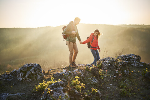 Paar auf einer Wanderung in den Bergen, das auf Felsen läuft, lizenzfreies Stockfoto