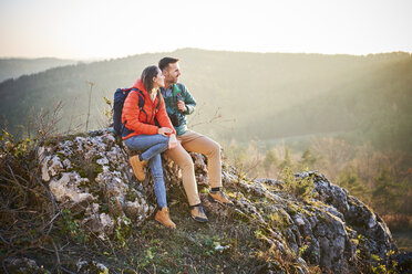 Couple on a hiking trip in the mountains having a break sitting on rock - BSZF00977