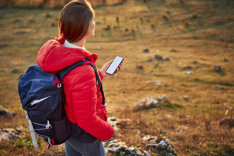 Frau mit Handy bei einer Wanderung in den Bergen, lizenzfreies Stockfoto