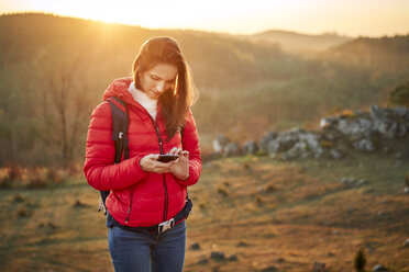 Woman on a hiking trip in the mountains using cell phone - BSZF00986