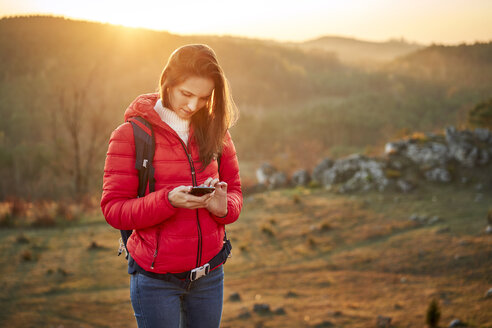 Frau beim Wandern in den Bergen, die ein Mobiltelefon benutzt - BSZF00986