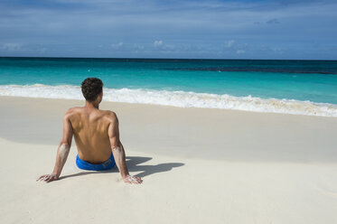 Karibik, Anguilla, Mann sitzt am Strand, Rückansicht - RUNF01170