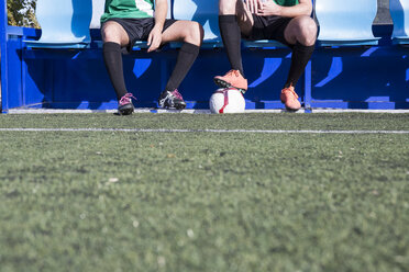 Beine von zwei Fußballspielern, die auf einer Bank am Fußballplatz sitzen - ABZF02176