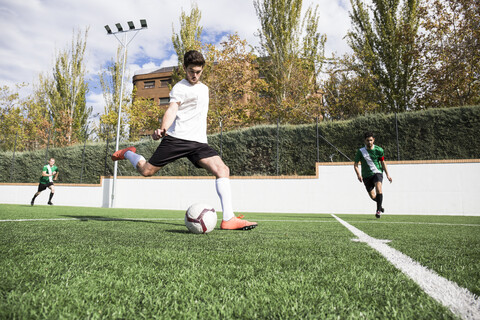 Fußballspieler schießt den Ball auf dem Fußballfeld, lizenzfreies Stockfoto