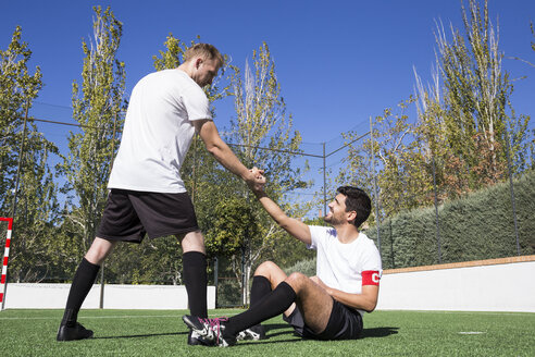 Football player helping an injured player during a match - ABZF02216