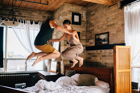 Pärchen springt auf Bett, lizenzfreies Stockfoto