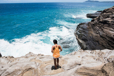 Woman exploring rocky coast, Spitting Caves, Oahu, Hawaii - ISF20699