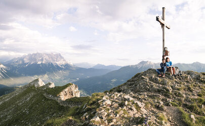 Austria, Tyrol, mother and son on a hiking trip with book at the summit - FKF03253