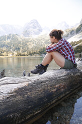 Österreich, Tirol, Frau auf Baumstamm sitzend am Seebensee - FKF03266