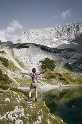 Austria, Tyrol, happy woman standing at lake Drachensee looking at view - FKF03277