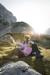 Österreich, Tirol, Mutter mit Tochter rastend in Berglandschaft bei Sonnenuntergang - FKF03284