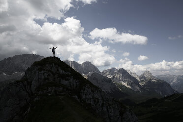 Austria, Tyrol, silhouette of man cheering on mountain peak - FKF03293