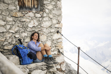 Austria, Tyrol, woman on a hiking trip resting at mountain hut with closed eyes - FKF03315