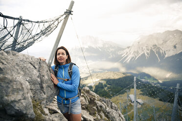 Österreich, Tirol, Frau auf Wandertour in den Bergen, stehend am Fels - FKF03323