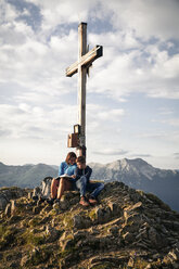 Österreich, Tirol, Mutter und Sohn beim Wandern mit Buch auf dem Gipfel - FKF03328