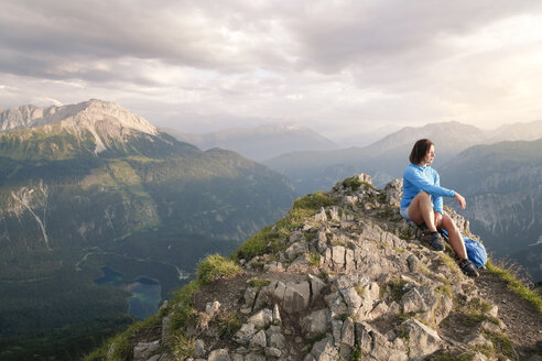 Österreich, Tirol, Frau auf Wandertour in den Bergen, auf einem Gipfel sitzend - FKF03332