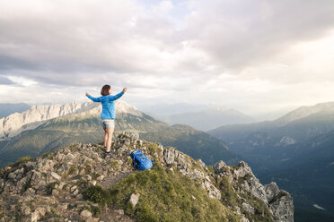 Austria, Tyrol, woman on a hiking trip in the mountains cheering on peak - FKF03333