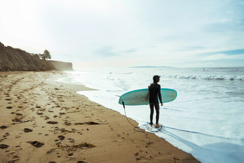 Surfer mit Surfbrett am Strand, Morro Bay, Kalifornien, Vereinigte Staaten, lizenzfreies Stockfoto