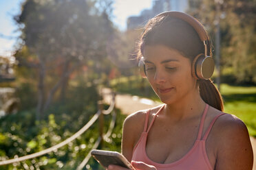 Woman listening to music with headphones in city park - ISF20866