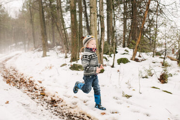 Junge läuft in Schneelandschaft durch Wald - ISF20876