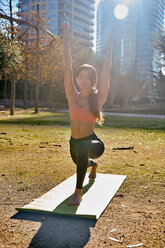 Woman practising yoga in city park, Barcelona, Catalonia, Spain - ISF20894