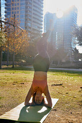 Woman practising yoga in city park, Barcelona, Catalonia, Spain - ISF20896