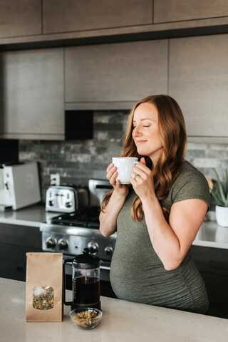 Schwangere Frau brüht Kräutertee mit französischer Presse, lizenzfreies Stockfoto