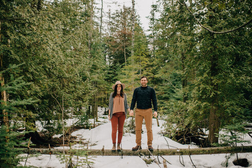 Couple standing on fallen tree trunk in forest, Tobermory, Canada - ISF20935