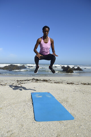 Sportliche Frau springt am Strand, lizenzfreies Stockfoto