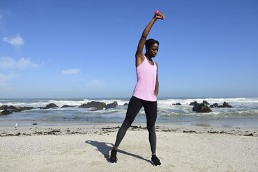Frau macht Fitnessübung mit Hantel am Strand - ECPF00445