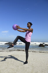 Frau macht Fitnessübungen mit Ball am Strand - ECPF00453