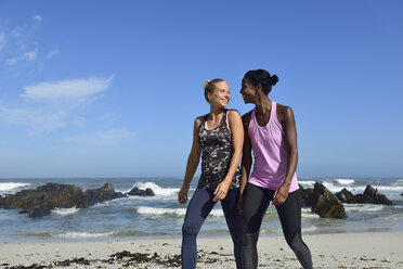 Zwei glückliche Frauen gehen am Strand spazieren - ECPF00460