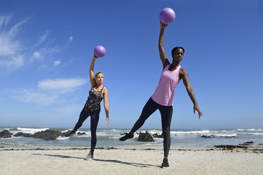 Zwei Frauen machen Fitnessübungen mit Ball am Strand - ECPF00465