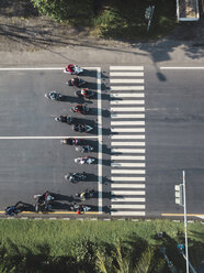 Indonesien, Bali, Sanur, Luftaufnahme von Motorrädern, die am Zebrastreifen auf der Straße warten - KNTF02664