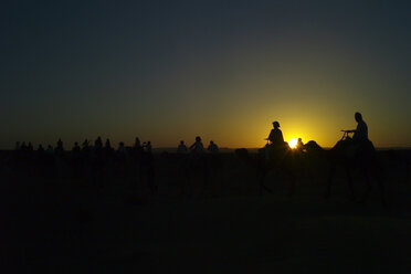 Marokko, Menschen auf Kamelen bei Sonnenuntergang - OCMF00279
