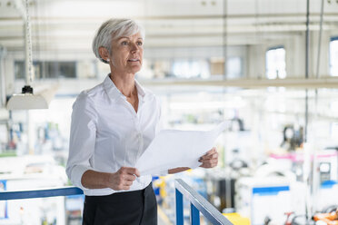 Senior woman holding plan in a factory - DIGF05737