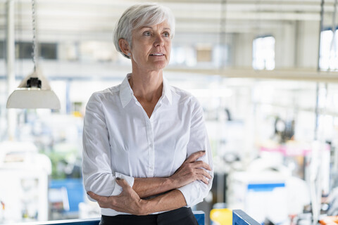 Porträt einer älteren Geschäftsfrau in einer Fabrik, die sich umschaut, lizenzfreies Stockfoto