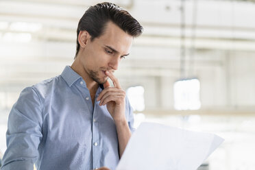 Businessman looking at plan in a factory - DIGF05743