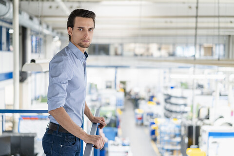 Porträt eines seriösen Geschäftsmannes im oberen Stockwerk einer Fabrik, lizenzfreies Stockfoto